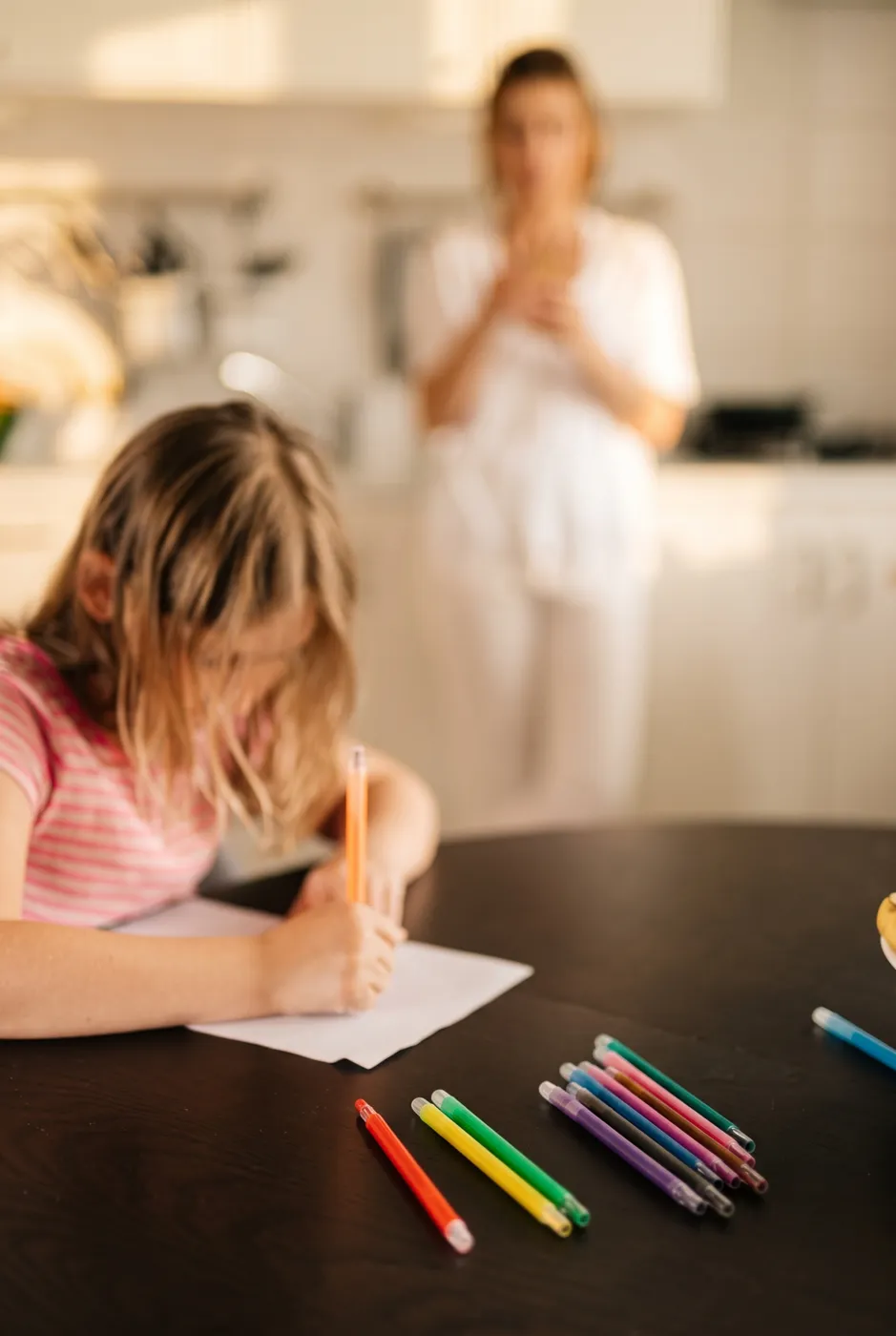 Una niña hace deberes en la mesa de la cocina
